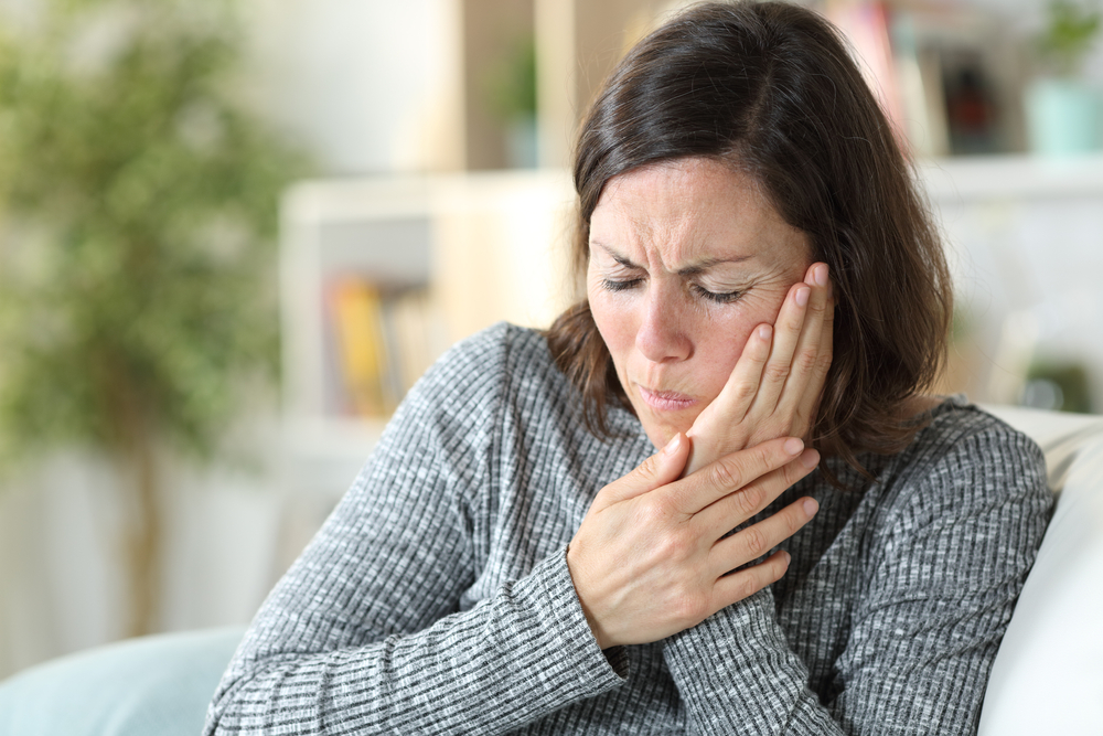 TMJ pain. Woman holding jaw in pain